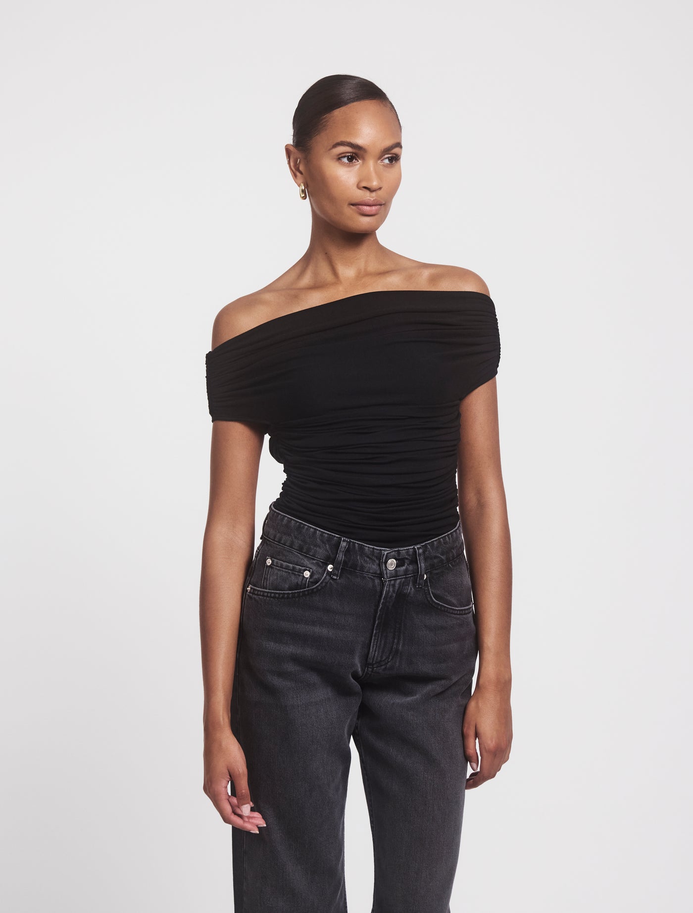 Angled view of Noho Top in Black, stylish off-shoulder fit